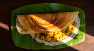 Crispy dosa filled with savory potato masala served on a vibrant green banana leaf showcases South Indian cuisine Organic Brown Rice Dosa Batter by Dream4Health